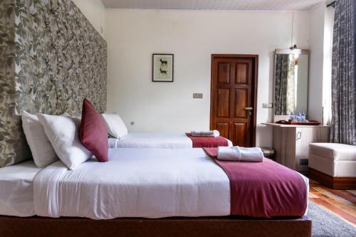 a bedroom with two beds with red and white pillows at The Wind Castle in Nuwara Eliya