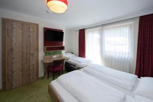 a hotel room with two beds and a desk at Pension Appartments Christoph in Westendorf