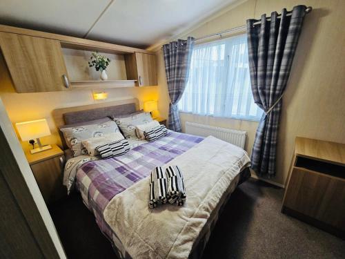 a small bedroom with a bed with blankets and pillows at The Canny View at Three Lochs Holiday Park in Balminnoch 3 bedroom sleeps upto 8 guests in Newton Stewart