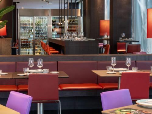 a restaurant with tables and chairs and a bar at Novotel Barcelona City in Barcelona