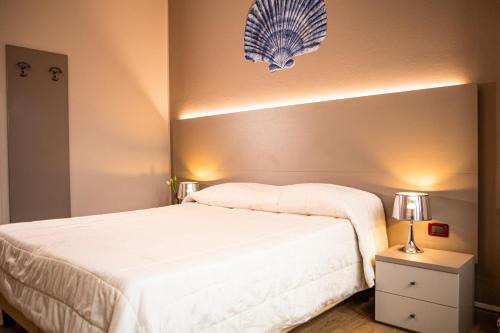 a bedroom with a large white bed and a lamp at Hotel Italia in Lerici
