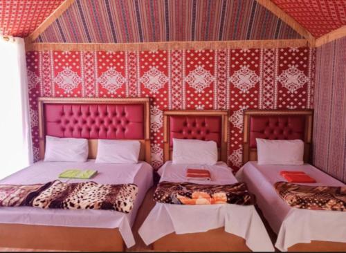 two beds in a room with red wallpaper at wadi rum land mars in Wadi Rum