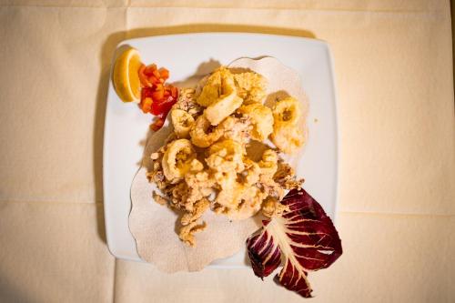 a plate of food with shrimp and a slice of lemon at Hotel Italia in Lerici