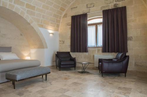 a hotel room with a bed and two chairs at Residence Masseria Santa Lucia in Matera