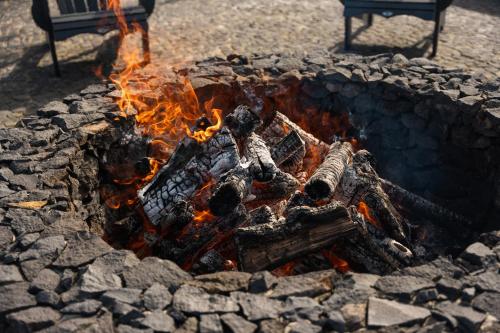 a fire burns in a stone fire pit with a bench at Azores Homes Resort & Spa in Ponta Delgada