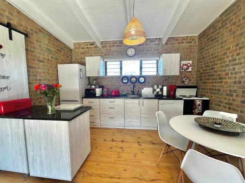 a kitchen with a counter and a table with chairs at Asem-Skep, Struisbaai in Struisbaai