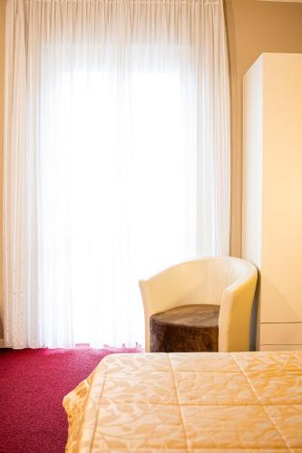 a bedroom with a bed and a chair and a window at Hotel Italia in Lerici