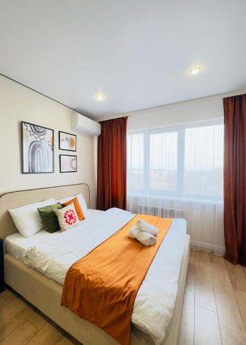a bedroom with a large bed with an orange blanket at Студия красивая in Almaty