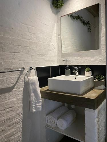 a bathroom with a sink and a mirror and towels at The Nook at Maboneng -24hr security, WiFi, cozy home in Johannesburg