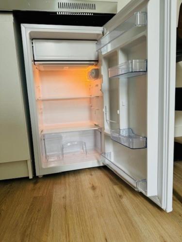 un réfrigérateur vide avec une porte ouverte dans une pièce dans l'établissement Appartement Basilique Saint Denys, à Argenteuil