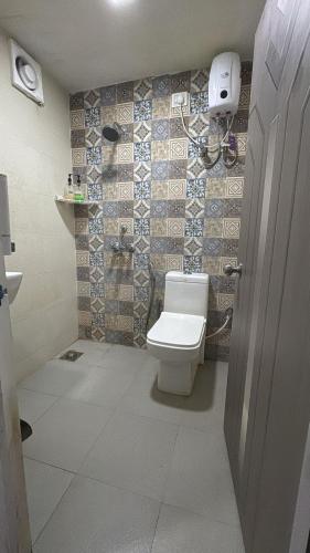 a bathroom with a toilet and a tile wall at Simple Belle by Half Orangee with Swimming Pool ,Near to Beach -Clubs - Hill Top best for Corporate Bookings-Summer vacation!! in Vagator