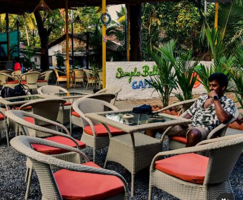 a man sitting at an outdoor table and chairs at Simple Belle by Half Orangee with Swimming Pool ,Near to Beach -Clubs - Hill Top best for Corporate Bookings-Summer vacation!! in Vagator