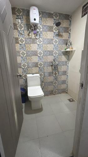 a bathroom with a toilet and a tiled wall at Simple Belle by Half Orangee with Swimming Pool ,Near to Beach -Clubs - Hill Top best for Corporate Bookings-Summer vacation!! in Vagator