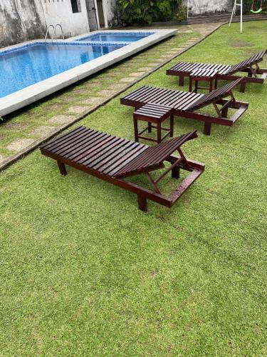 three picnic tables sitting on the grass near a swimming pool at Résidence Victorine in Douala