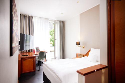 a hotel room with a bed and a desk and a television at Kochs Stadthotel in Olpe