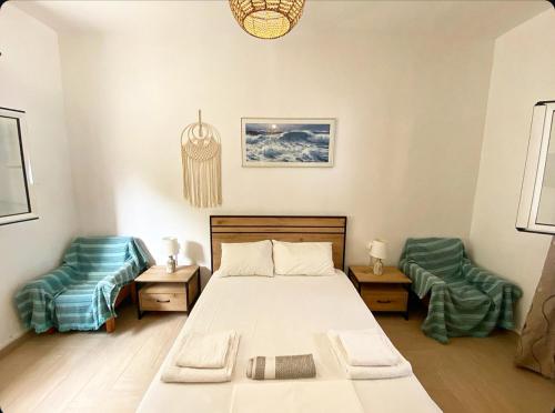 une chambre avec un lit et deux chaises dans l'établissement Πέτρινη αυλή, Αρμενιστης Ικαρια, à Armenistis