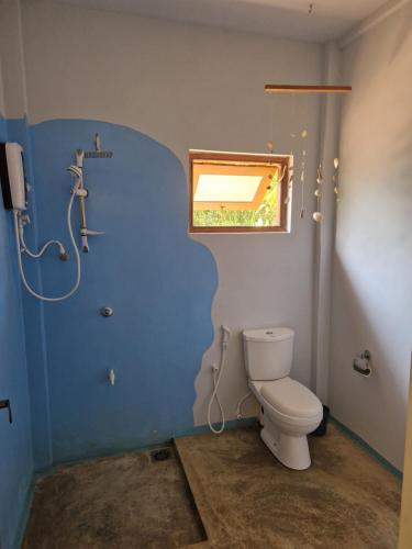 a bathroom with a toilet and a window at Nature Paradise Guesthouse in Waikkal
