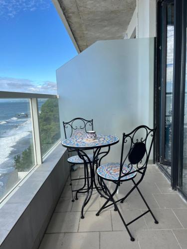 a table and two chairs on a balcony with the ocean at Bamboo Beach Tsikhisdziri Seaview Flat 838 in Tsikhisdziri