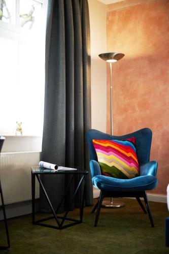 a blue chair with a colorful pillow next to a lamp at Kochs Stadthotel in Olpe