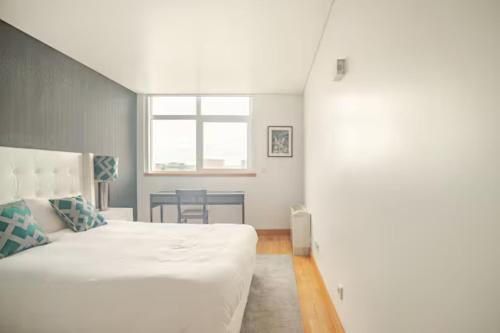 a bedroom with a white bed and a table at Caravela - Torre Sao Rafael in Lisbon