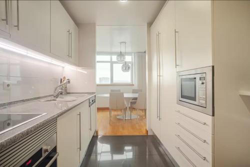 a white kitchen with a sink and a microwave at Caravela - Torre Sao Rafael in Lisbon