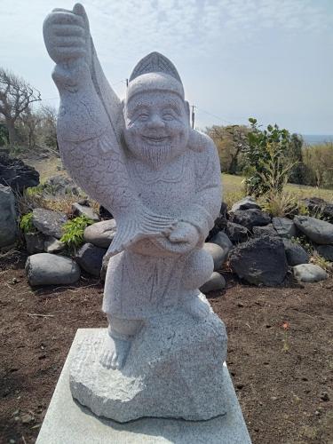 a statue of a person sitting on a rock at AJITO in Oshima