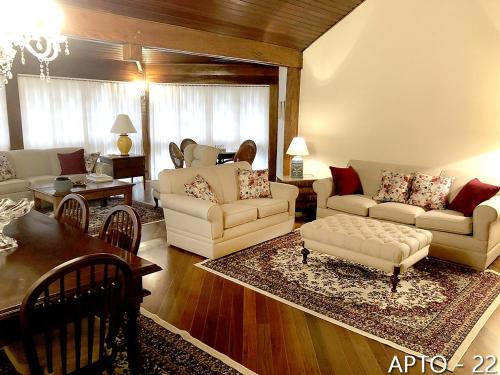 a living room with white couches and a table at Center Suiço Flats in Campos do Jordão
