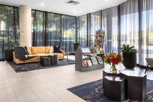 a lobby with couches and chairs and windows at Quest Macquarie Park in Sydney