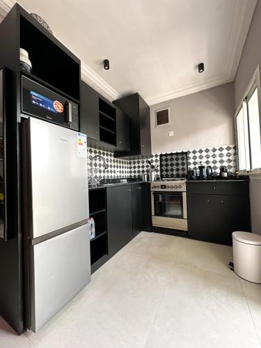 a kitchen with black cabinets and a white refrigerator at Résidence Victorine in Douala
