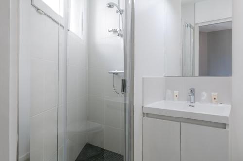 a white bathroom with a sink and a shower at Hotel Foch Nancy Gare in Nancy