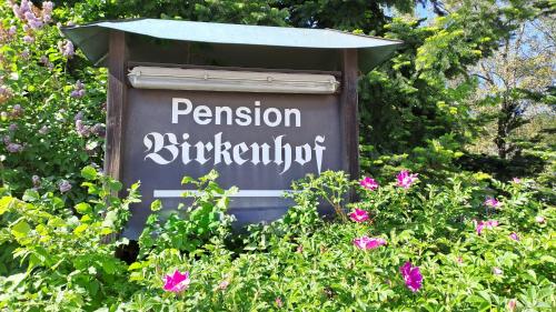 a sign for a pension administrator in a field of flowers at Pension Birkenhof in Hengersberg