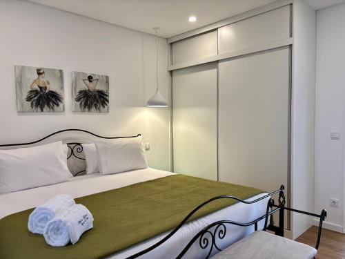 a bedroom with a bed with a green blanket at Azores Homes Resort & Spa in Ponta Delgada