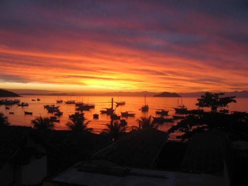 una puesta de sol con muchos barcos en el agua en Cesar Apartamentos, en Búzios
