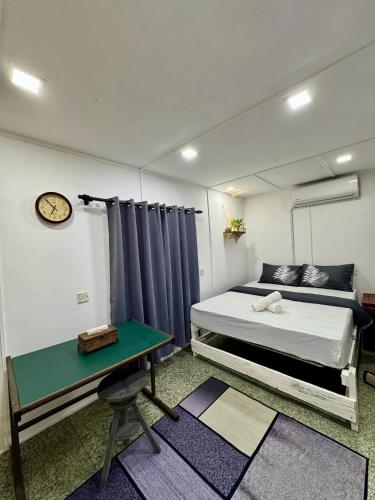a bedroom with a bed and a table and a clock at Pok Mat Beach Cabin in Marang