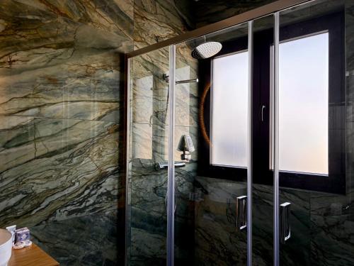 a bathroom with a shower with a stone wall at Azores Homes Resort & Spa in Ponta Delgada
