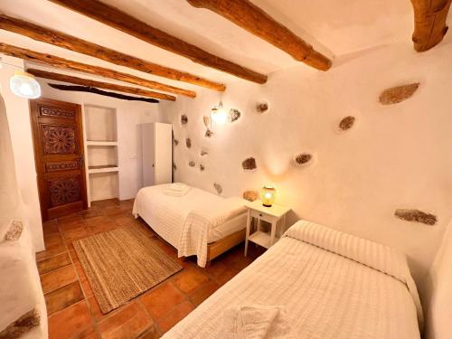 a bedroom with two beds and a table in a room at Cortijo Al-Andalus in Órgiva