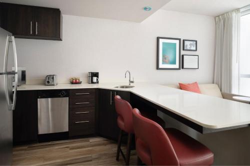 a kitchen with a sink and a counter with red chairs at Residence Inn by Marriott Miami Beach Surfside in Miami Beach