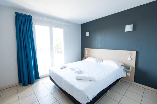 a bedroom with a large white bed with blue walls at Comfort Aparthotel Frejus La Tour de Mare in Fréjus