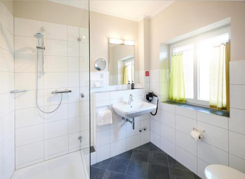 a white bathroom with a sink and a shower at Kochs Stadthotel in Olpe