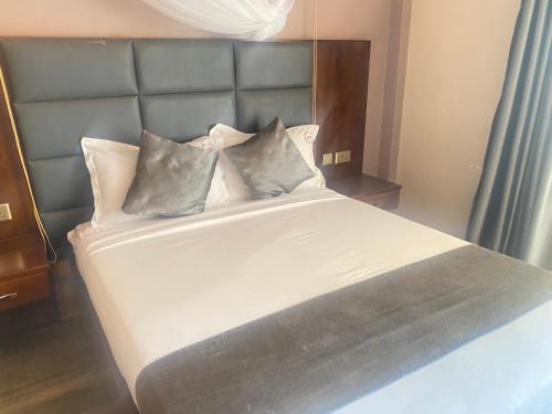 a bed with four pillows on it in a room at Jinna Suites Hotel in Mukono