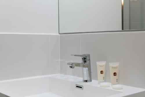 a bathroom sink with a faucet and a mirror at Hotel Foch Nancy Gare in Nancy