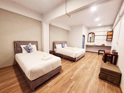 a hotel room with two beds and a table at Hometown Stays Hatyai in Hat Yai