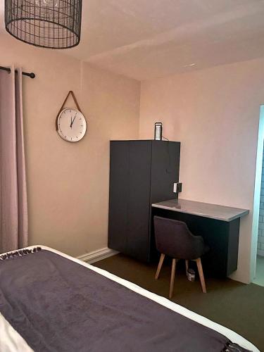 a bedroom with a desk and a clock on the wall at Mount Road Suites in Port Elizabeth