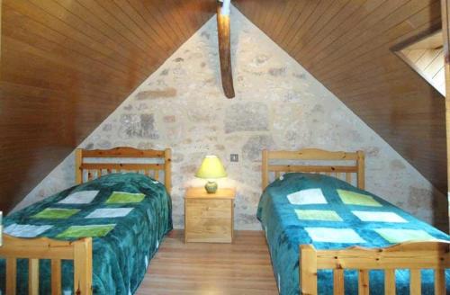 two beds in a room with a stone wall at Canterane, un coin de paradis à la campagne in Salignac Eyvigues