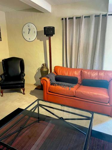 a living room with a couch and a clock at Mount Road Suites in Port Elizabeth
