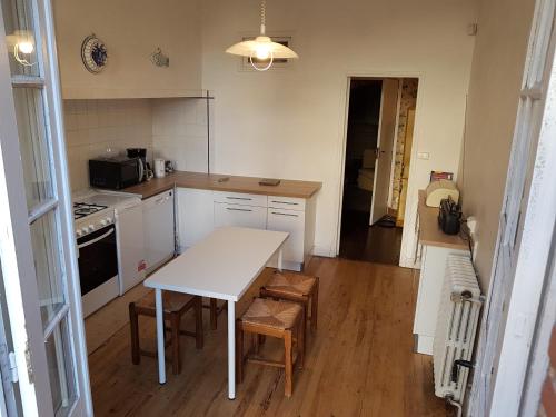 - une cuisine avec une table et des chaises blanches ainsi qu'une cuisinière dans l'établissement La tour du Griffoul, à Gaillac