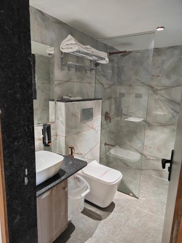 a bathroom with a sink and a toilet and a shower at Hotel The Grand View,Gandhinagar in Gandhinagar