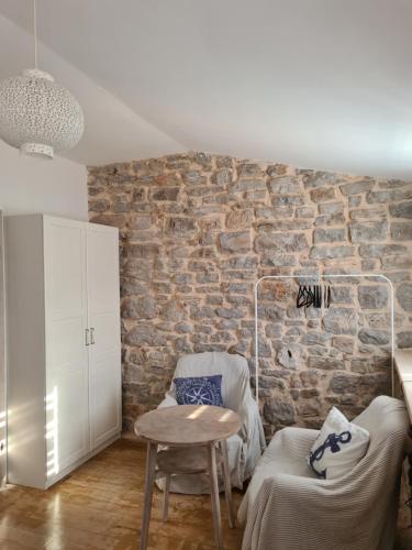 a living room with a table and a brick wall at Apartment Salvia - Stivan, Cres - 900 m to Merascica beach in Štivan