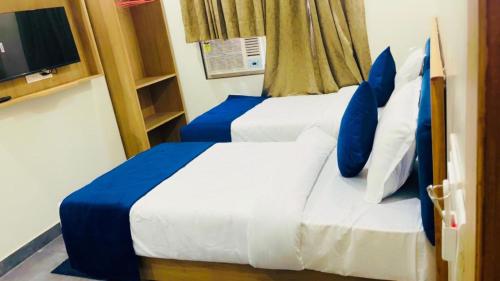 a bedroom with two beds with blue pillows and a tv at Hotel The Rise At Delhi Airport in New Delhi