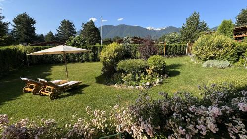 a garden with an umbrella and chairs and flowers at Villa - VALL DI VALL in Pirin Golf & Country Club in Razlog
